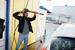 South asian man or indian male washing his white transportation on car wash.