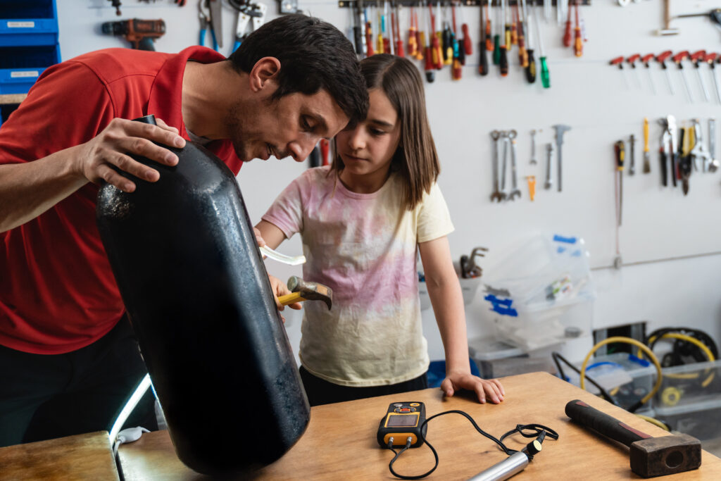 Father and daughter working at diving workshop center - Diver tank visual inspection - Focus on girl face