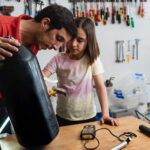 Father and daughter working at diving workshop center - Diver tank visual inspection - Focus on girl face