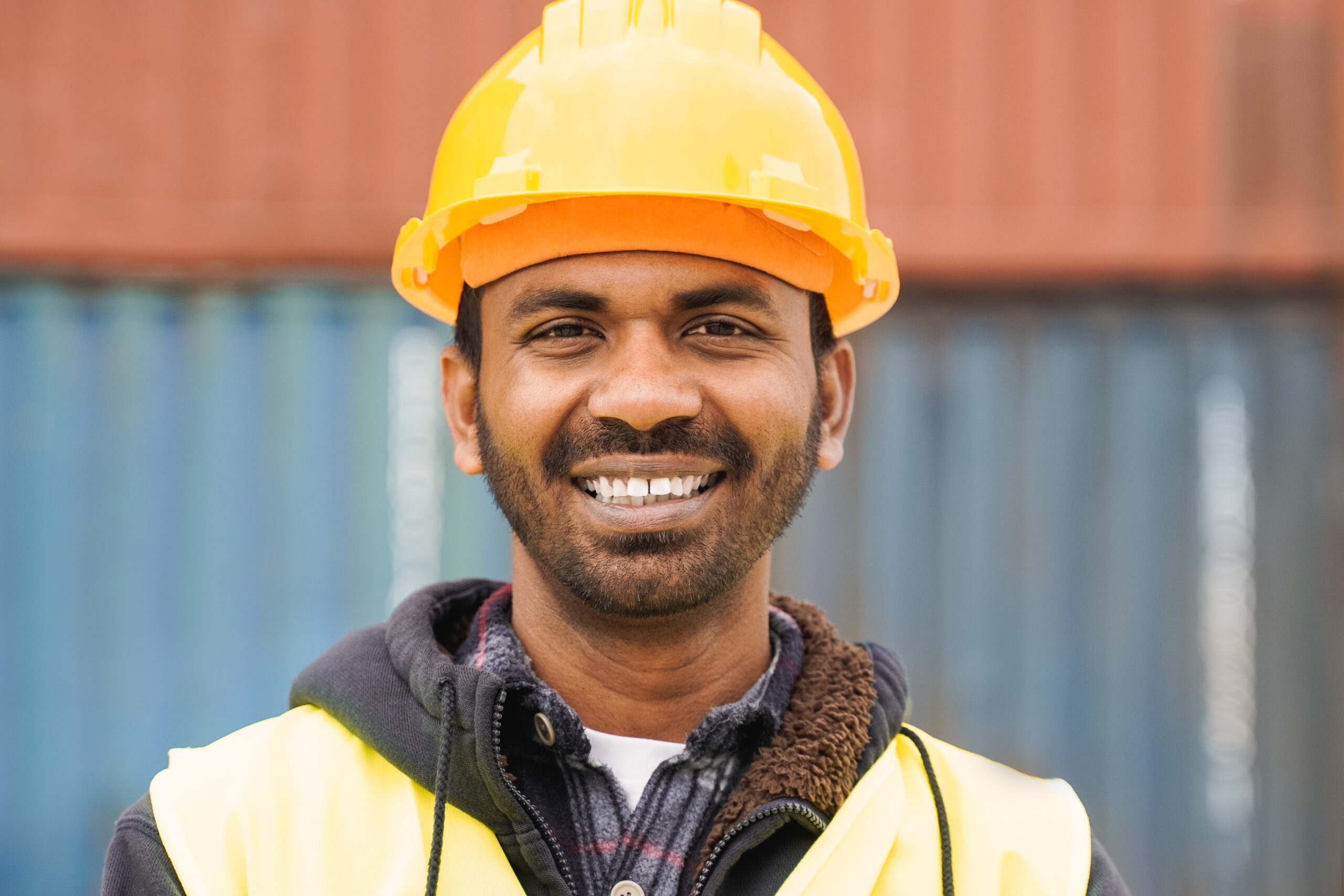 Happy Indian industrial worker man smiling at camera at shipping freight terminal port - Focus on face