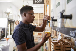 Man Filling Container With Dishwasher Powder In Plastic Free Grocery Store